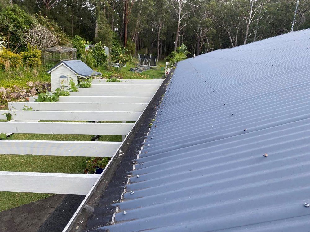 A Blue Roof With A Gutter On The Side Of It — The Guttering Cleaning Man in Harrington, NSW