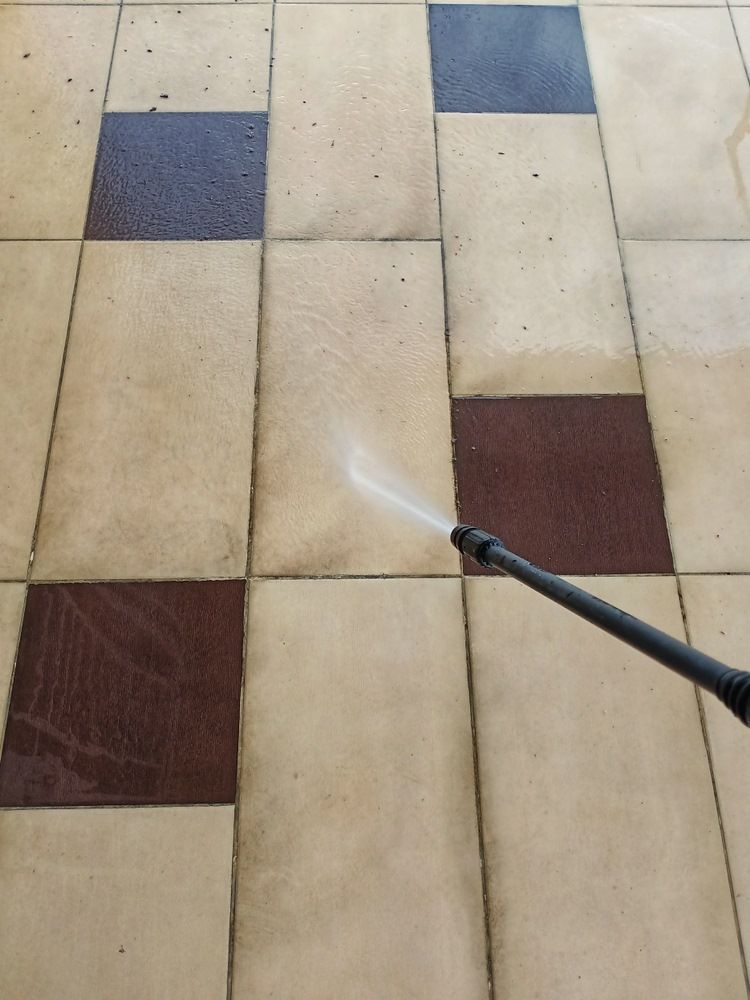 A Person Is Cleaning A Tiled Floor With A High Pressure Washer — The Guttering Cleaning Man in Harrington, NSW