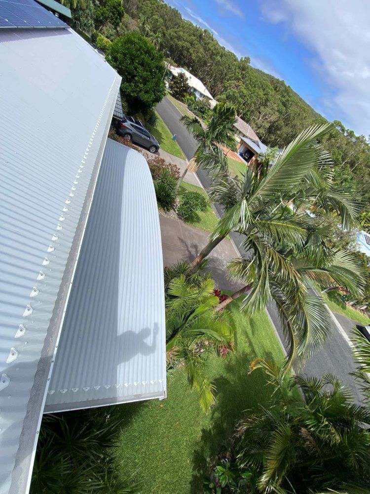 An Aerial View Of A House With A White Roof And A Palm Tree — The Guttering Cleaning Man in Tuncurry, NSW