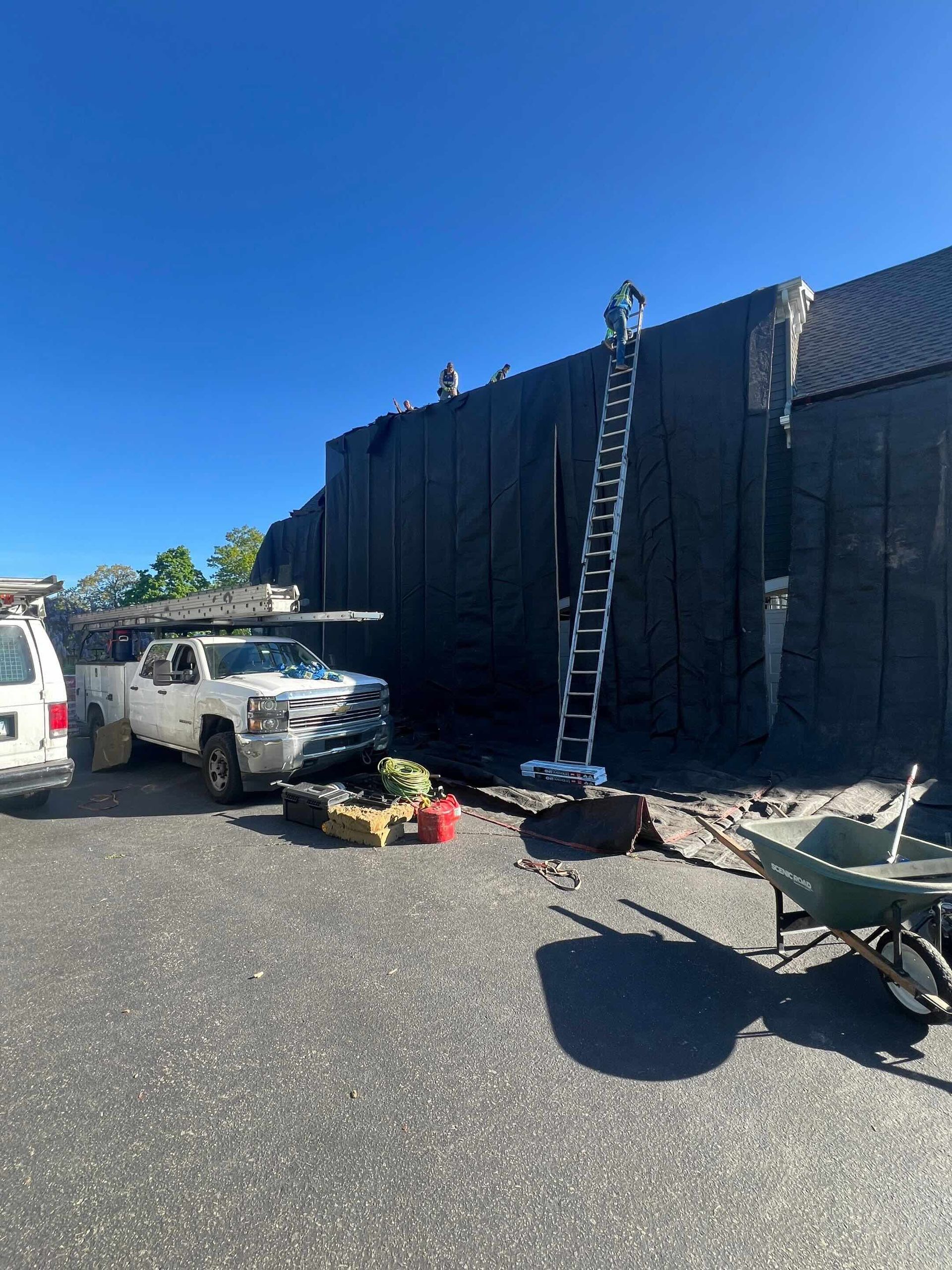 Crew using thick tarps to protect house from falling debris