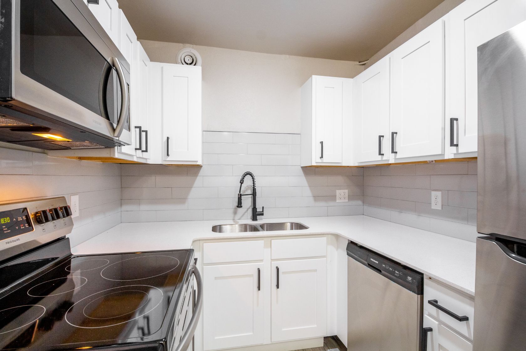 Bright, white kitchen with stainless steel appliances and dark hardware.