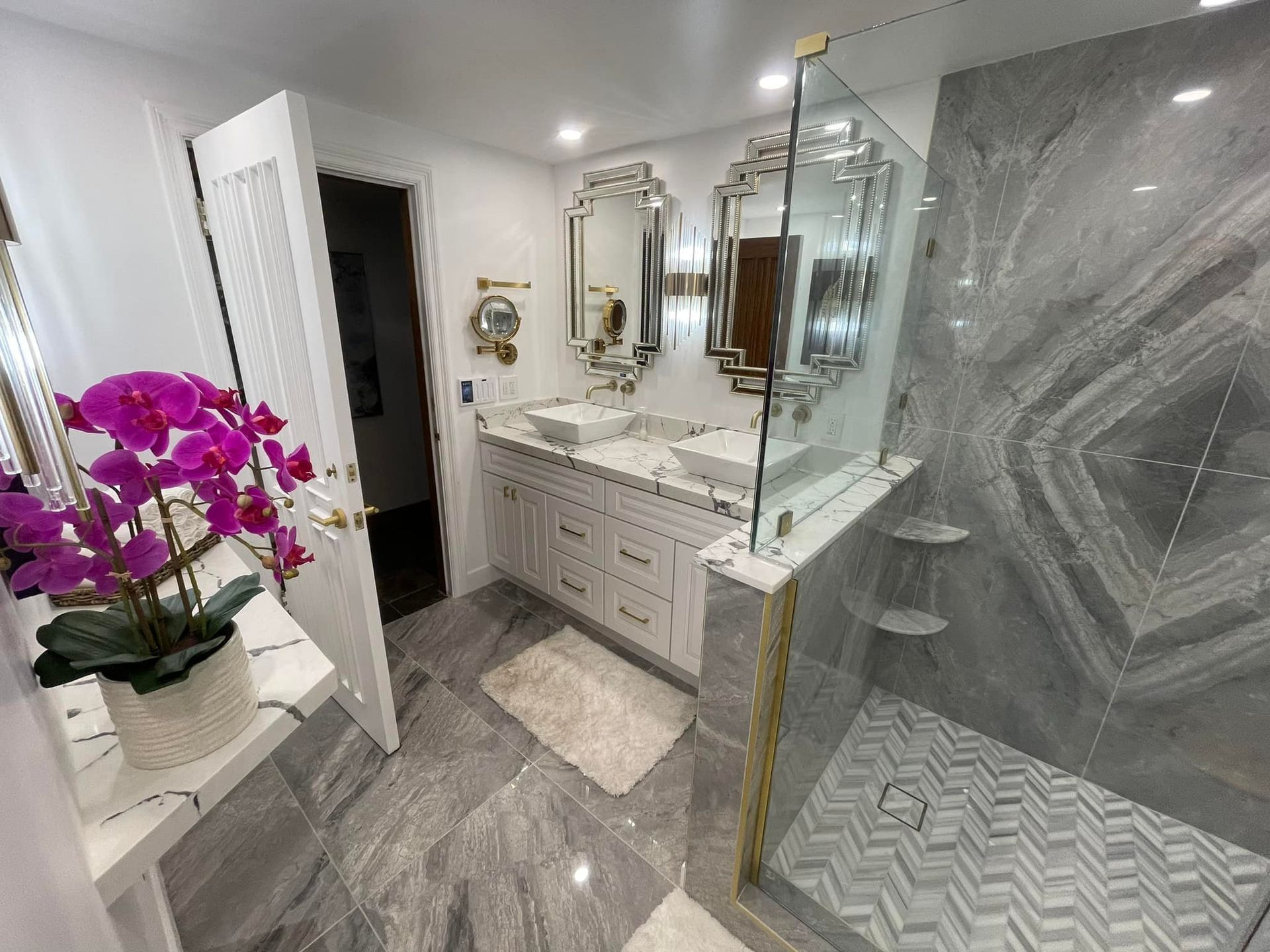 Modern bathroom with shower, dual sinks, and white cabinets. Gray, white, and tan color scheme.