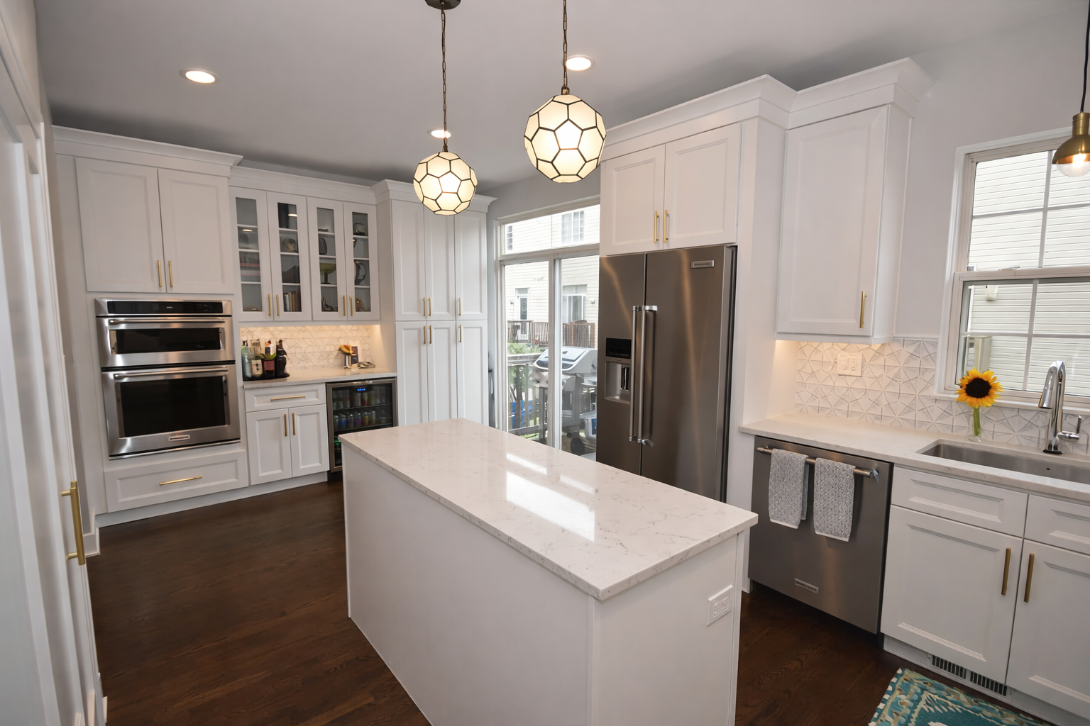 White kitchen with island, stainless steel appliances, and pendant lights.