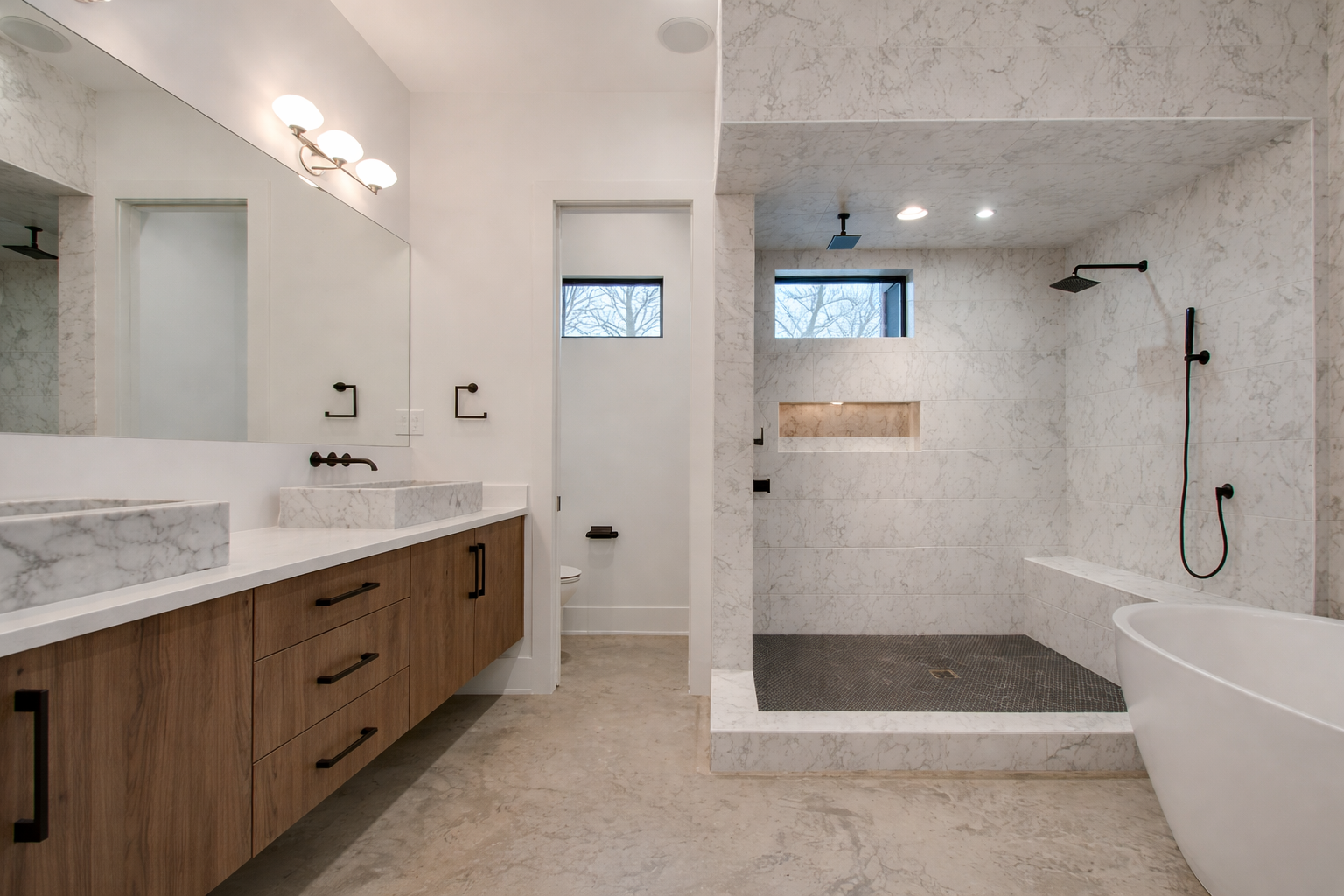 Modern bathroom with a double vanity, large shower, and soaking tub. Light wood cabinets, stone tile.