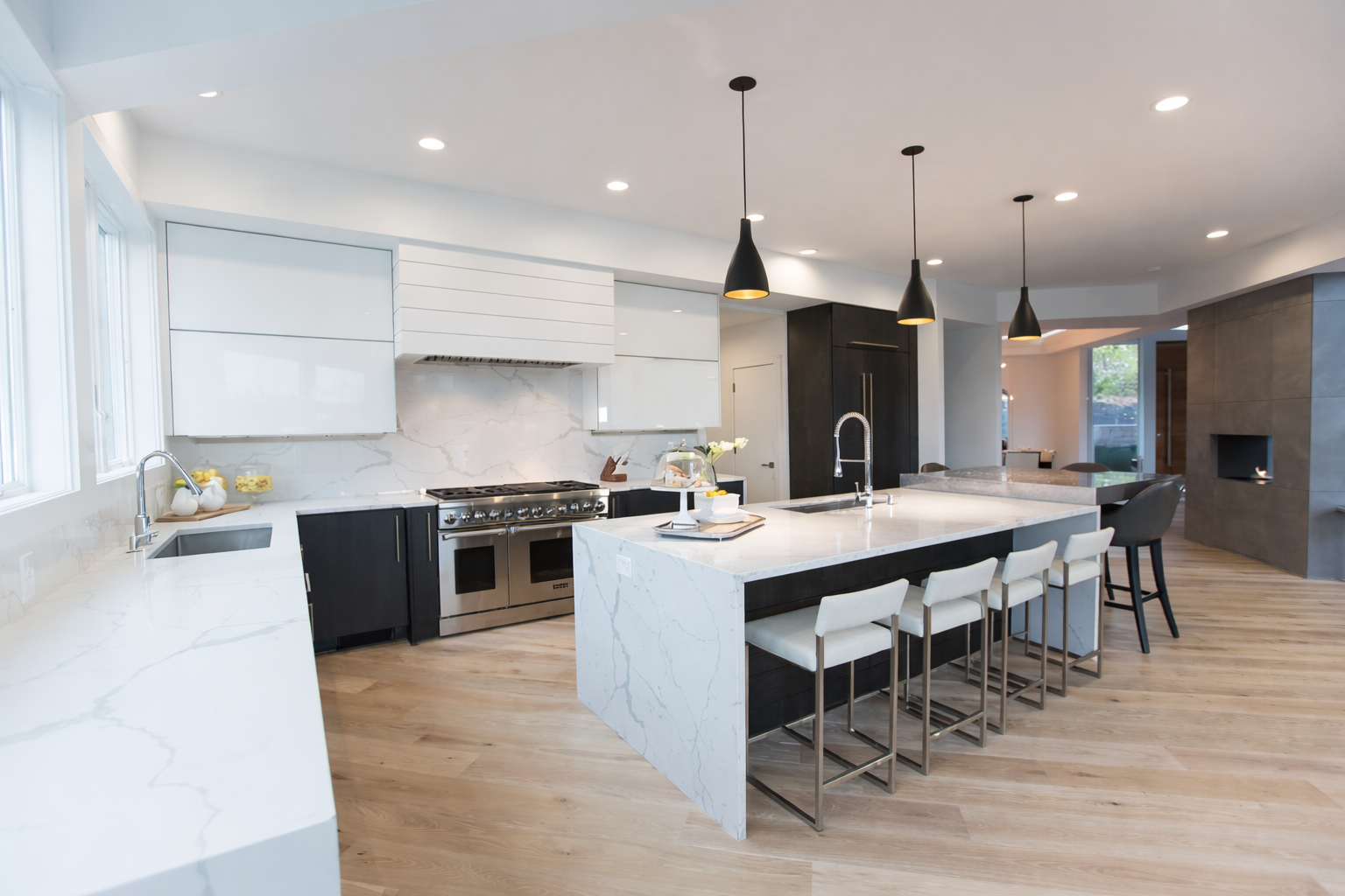 Modern kitchen with white countertops, black cabinets, and a large island with pendant lights.