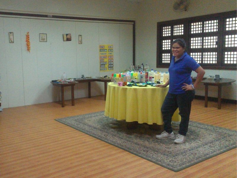 A woman in a blue shirt stands in front of a table with a yellow table cloth