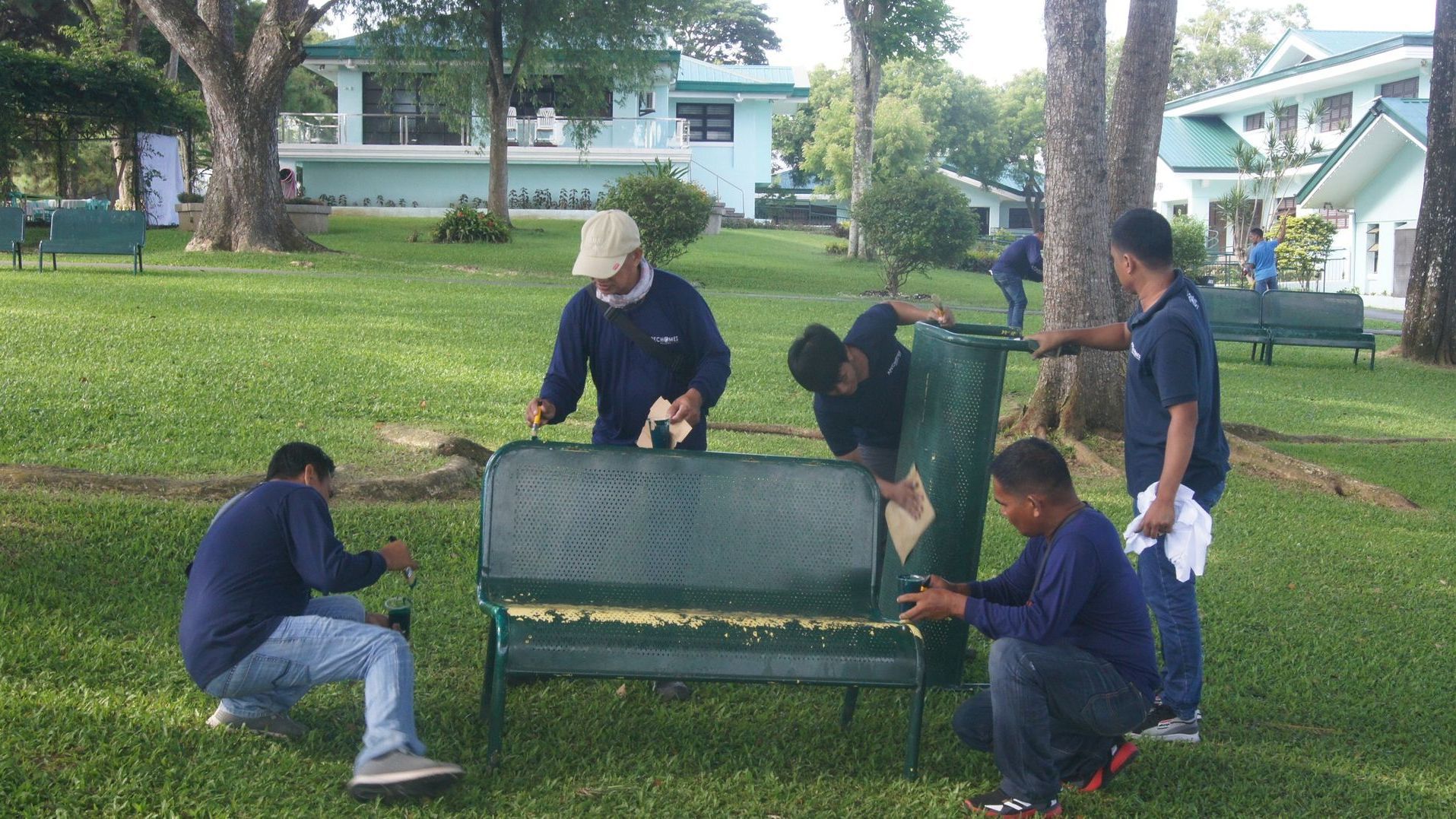 A group of men are working on a park bench