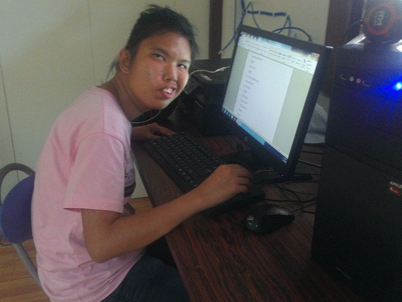 A woman in a pink shirt is typing on a computer