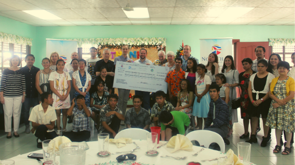 A group of people are standing around a table holding a large check.