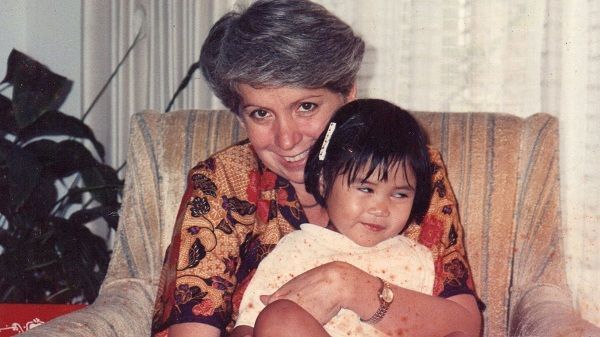 A woman is holding a little girl in her arms while sitting in a chair.
