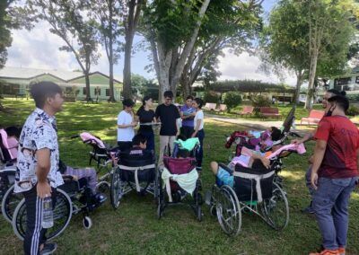 A group of people in wheelchairs are standing in a park.