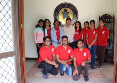A group of people posing for a picture in front of a sign that says chosen children age