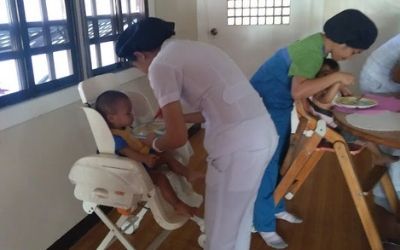 A woman is feeding a baby in a high chair