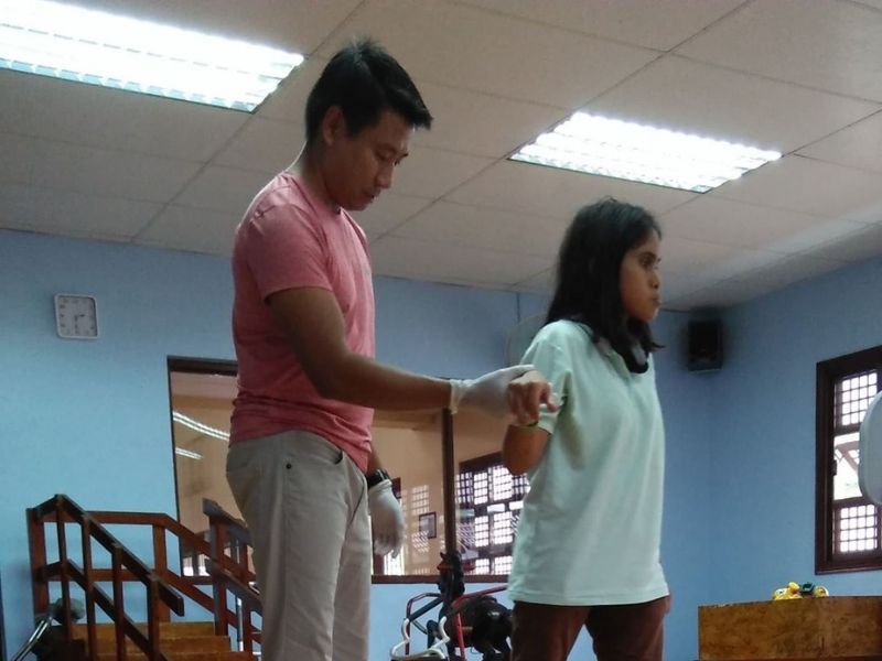 A man in a pink shirt is helping a girl in a white shirt