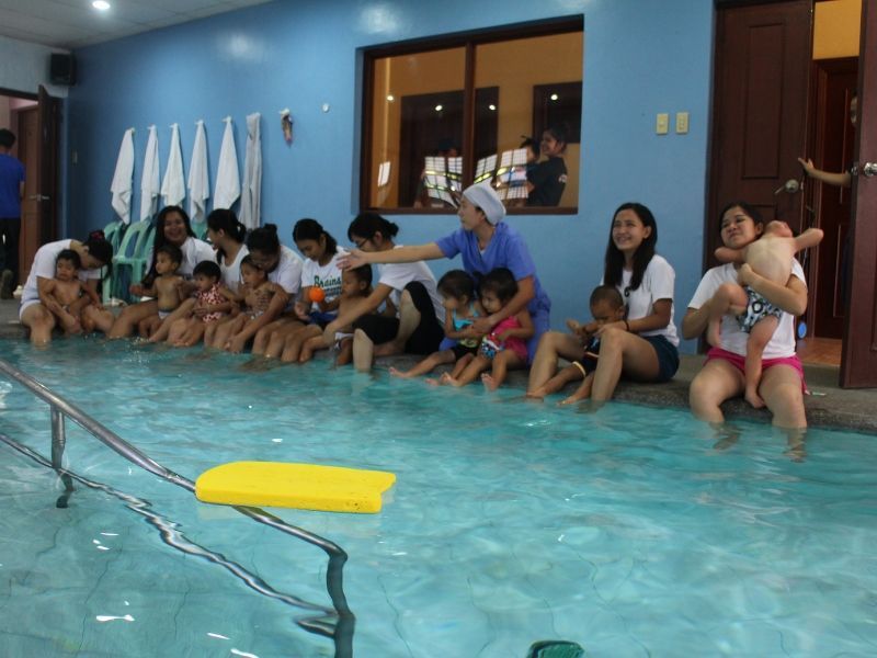 A group of people are sitting around a swimming pool