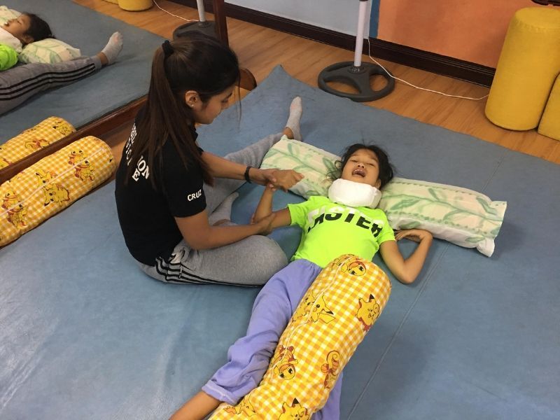 A woman is sitting on the floor with a child who is laying on a pillow.