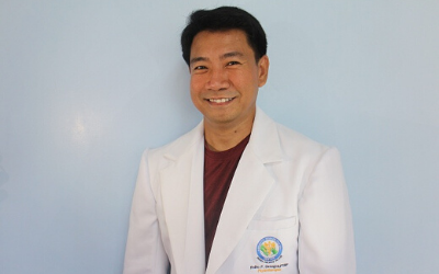 A man in a white lab coat is smiling for the camera