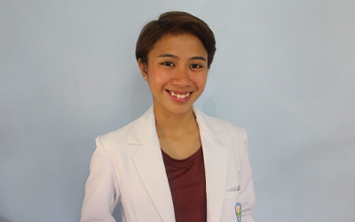 A woman in a white lab coat is smiling for the camera.