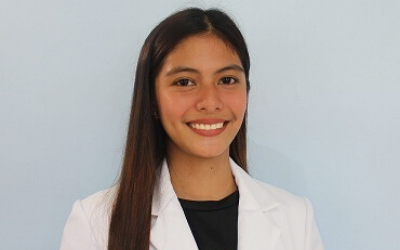 A woman in a white coat is smiling for the camera.