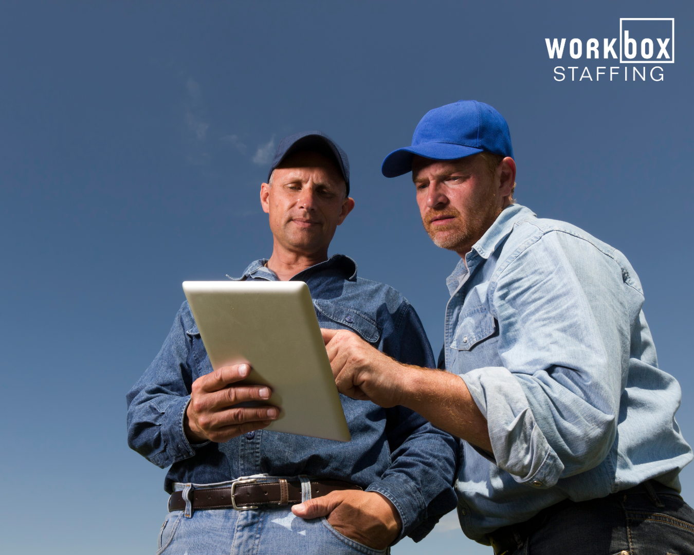 Two men are looking at a tablet together.