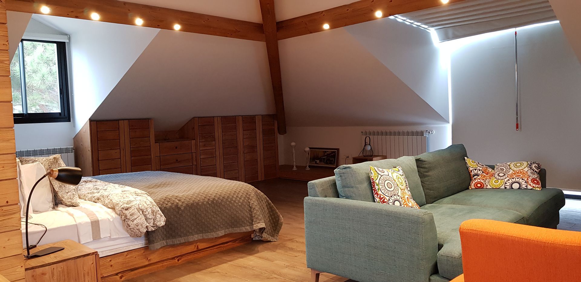Bedroom with bed, sofa, wood ceiling, and window.