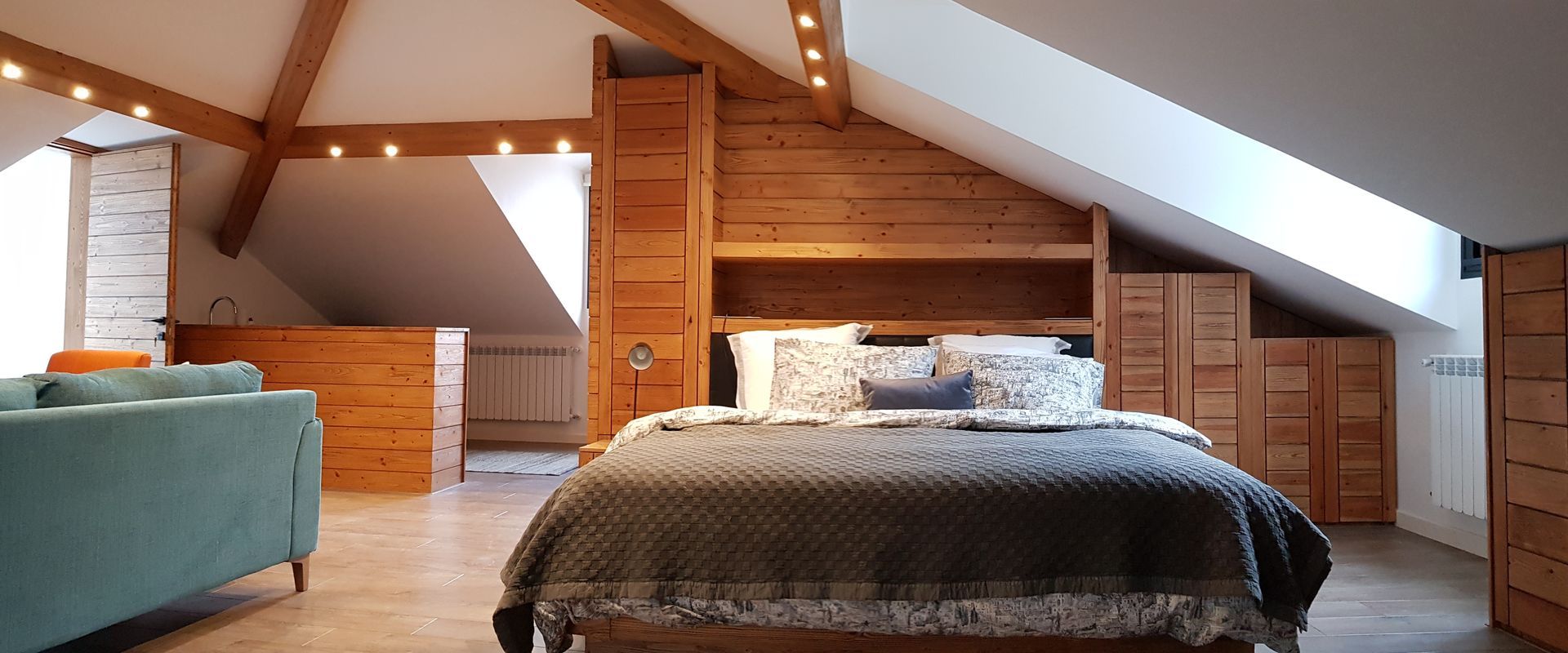 Bedroom with wood accents, a slanted ceiling, and a bed with a patterned comforter.
