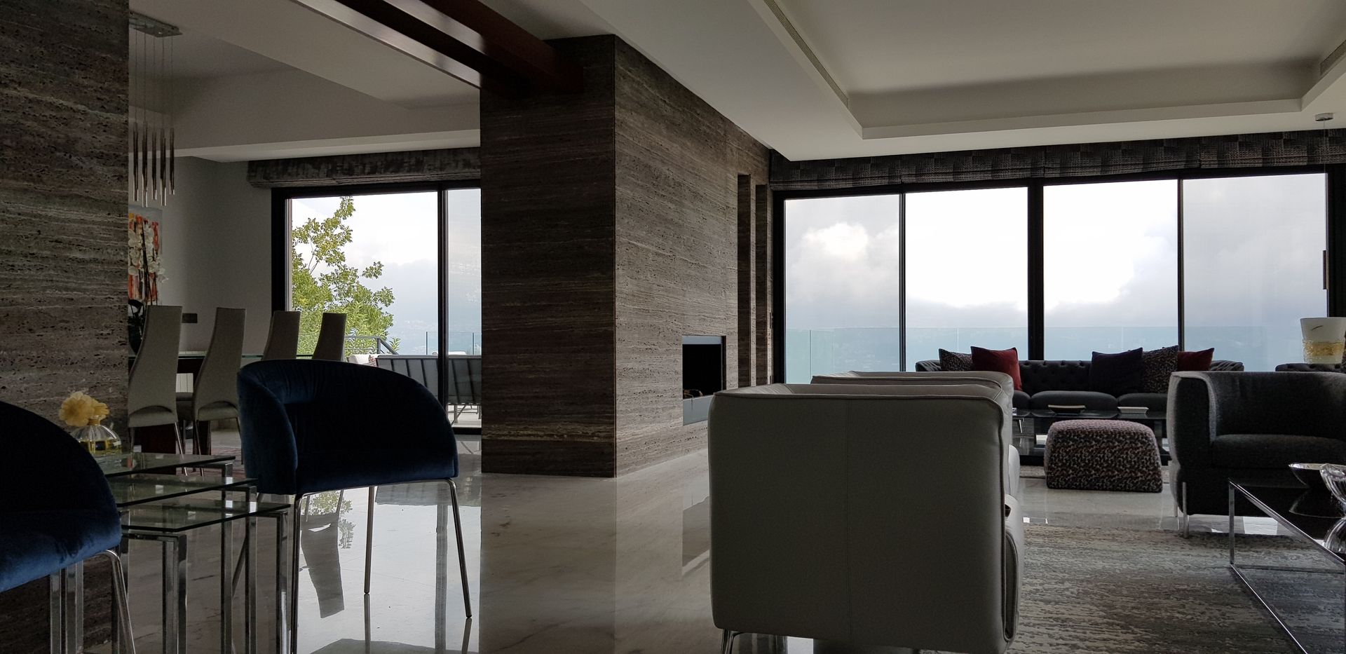 Living room with floor-to-ceiling windows overlooking a view of the ocean.  Modern furniture and marble floors.