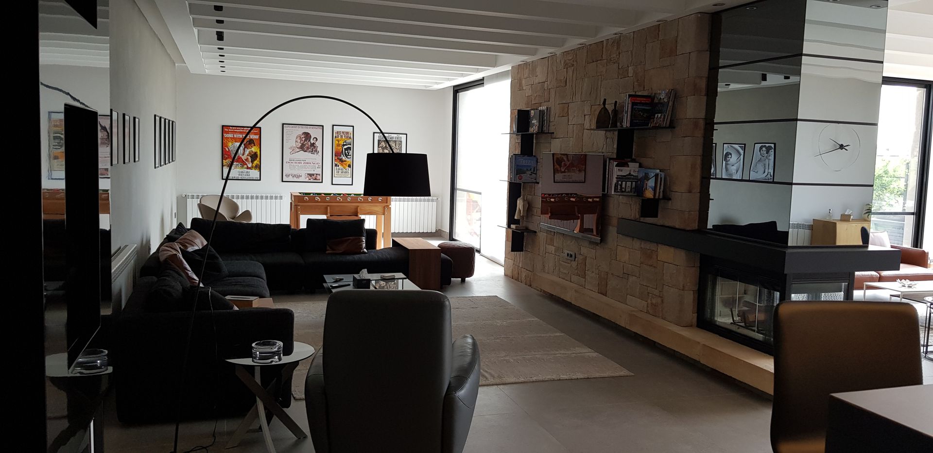 Modern living room with dark furniture, art, and stone accent wall.