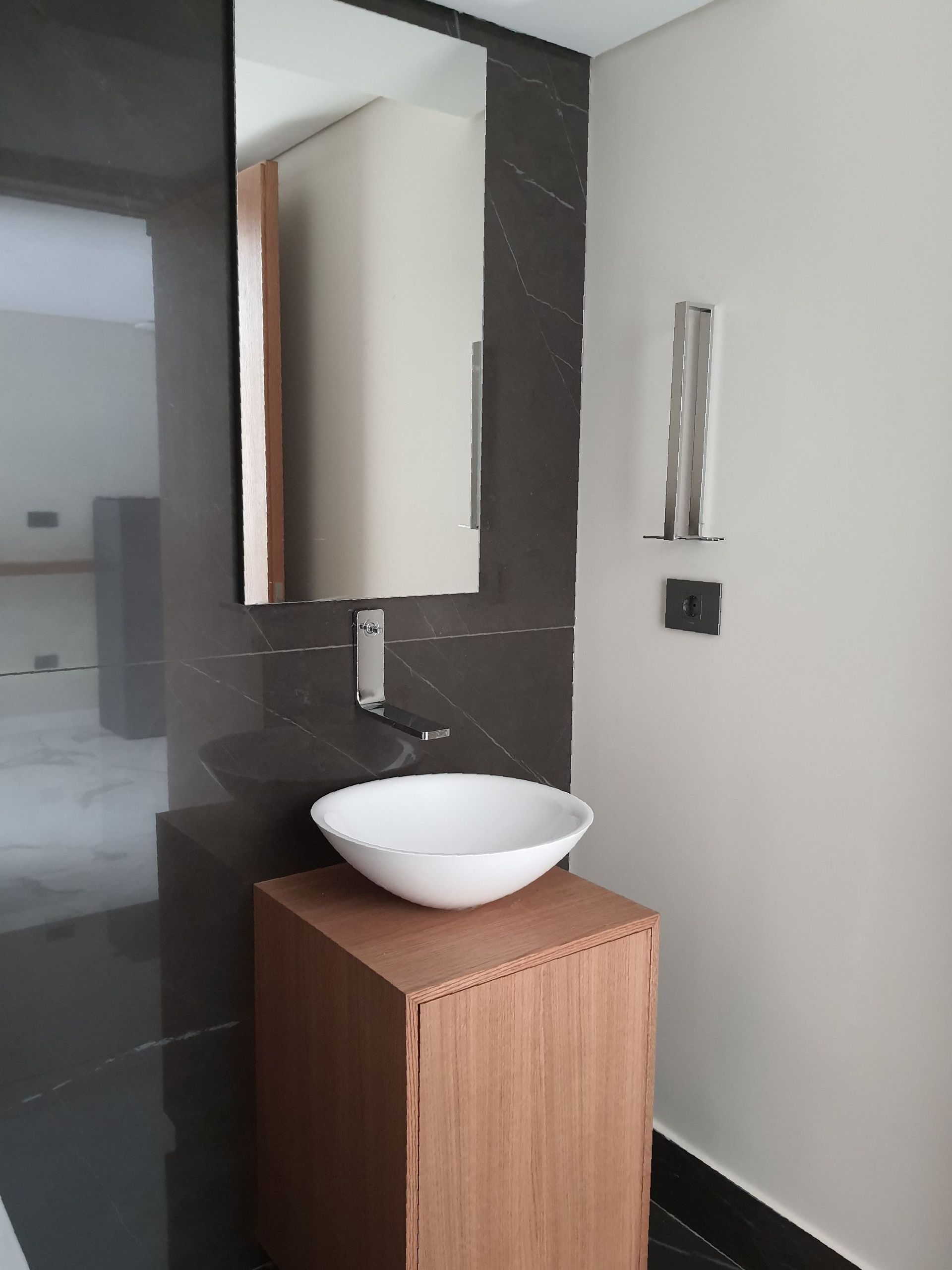 Bathroom with a white bowl sink, wood cabinet, dark gray wall, and mirror.