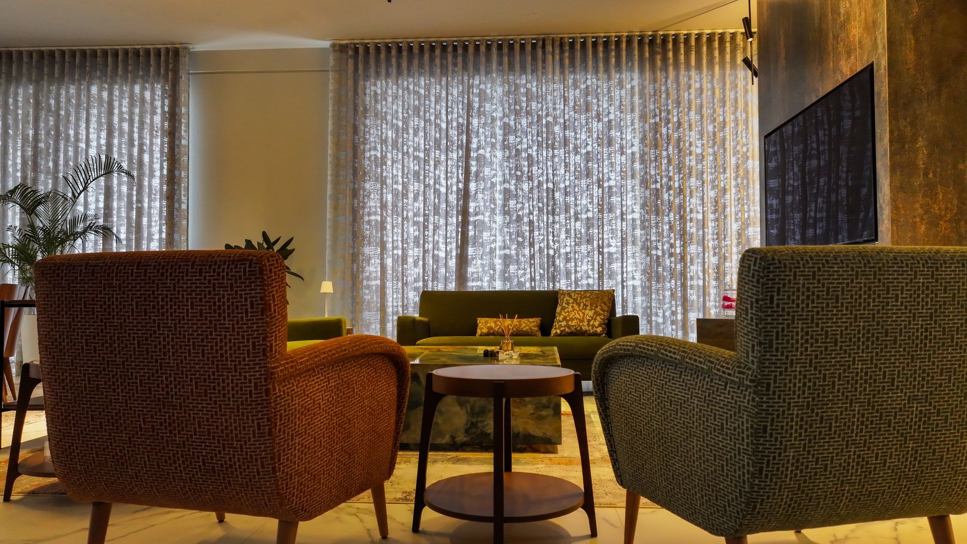 Cozy living area with patterned curtains, two armchairs, a sofa, and a small table.