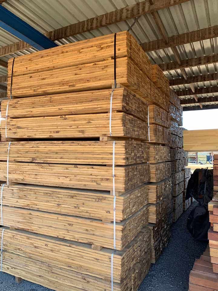 A Stack Of Wooden Beams Sitting Under A Roof — Perry's Timber & Fencing In Dapto, NSW