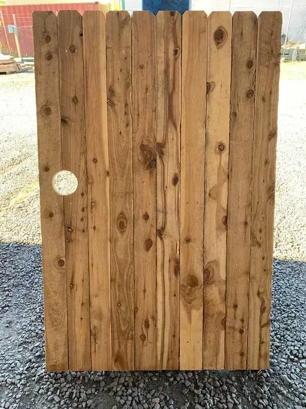 A Wooden Fence Is Sitting On Top Of A Gravel Road — Perry's Timber & Fencing In Dapto, NSW