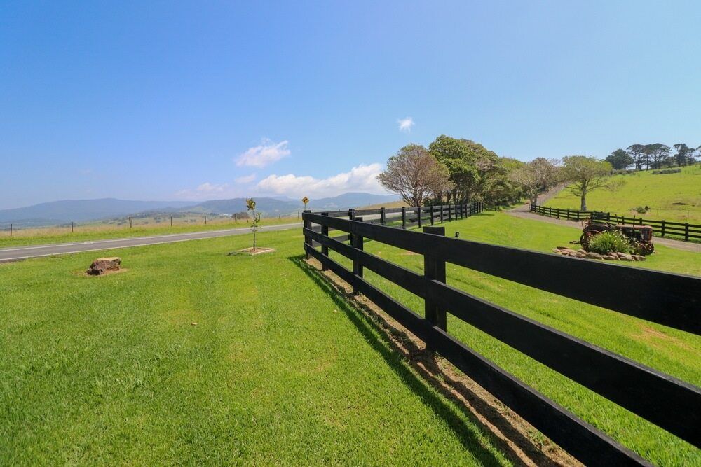 A Black Wooden Fence Surrounds A Lush Green Field — Perry's Timber & Fencing In Dapto, NSW