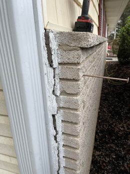 Wall section repair: A person uses a drill to fasten a concrete wall to siding.