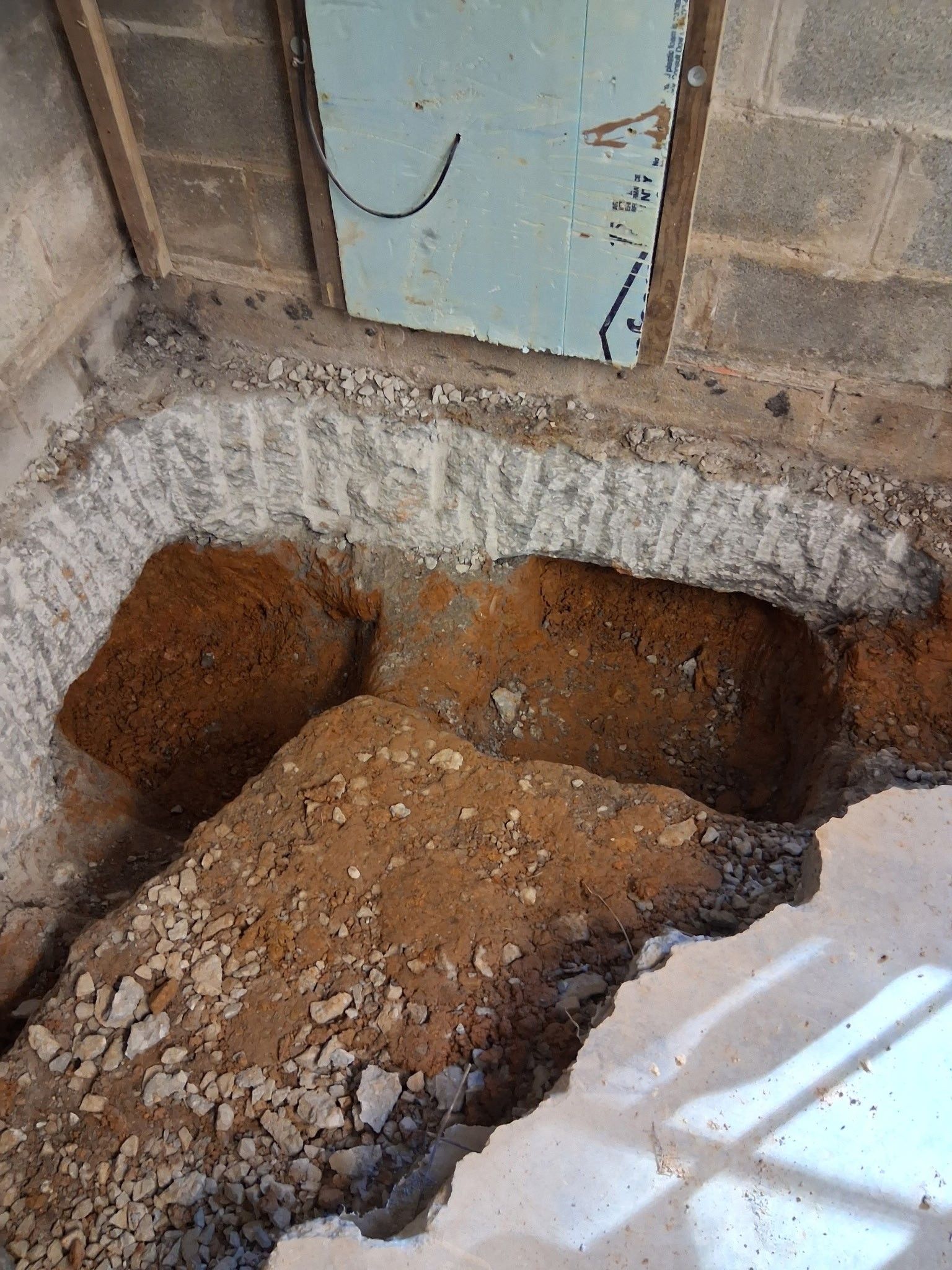 Wall section repair: A person uses a drill to fasten a concrete wall to siding.