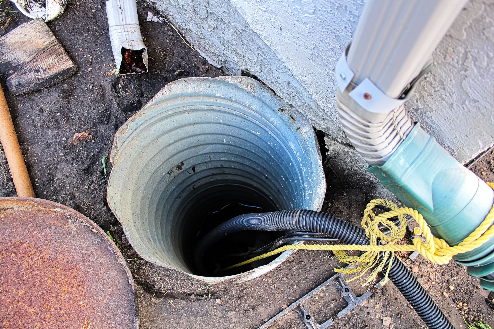Looking down a corrugated pipe, black hose inside. Connected to a green gutter spout.