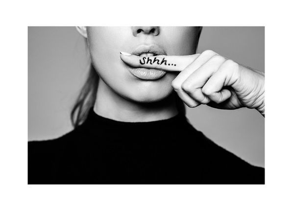 A black and white photo of a woman covering her mouth with her finger ..