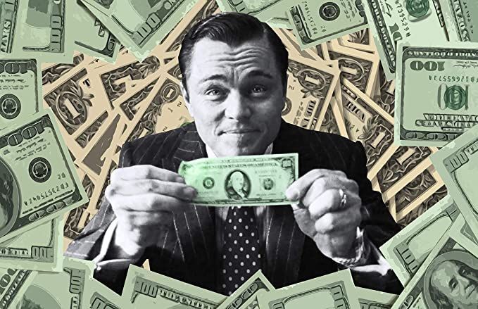 A man is holding a dollar bill in front of a pile of money