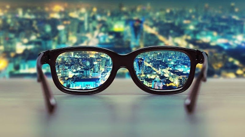 A pair of glasses with a reflection of a city in the lenses.