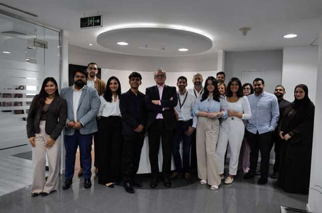 A group of people are standing around a table looking at a tablet.