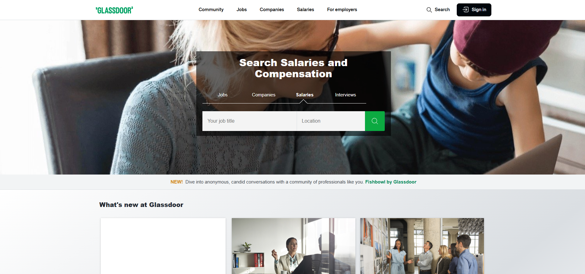 A woman is sitting at a desk using a laptop computer.