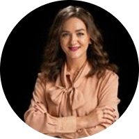 A woman is standing in a circle with her arms crossed and smiling.