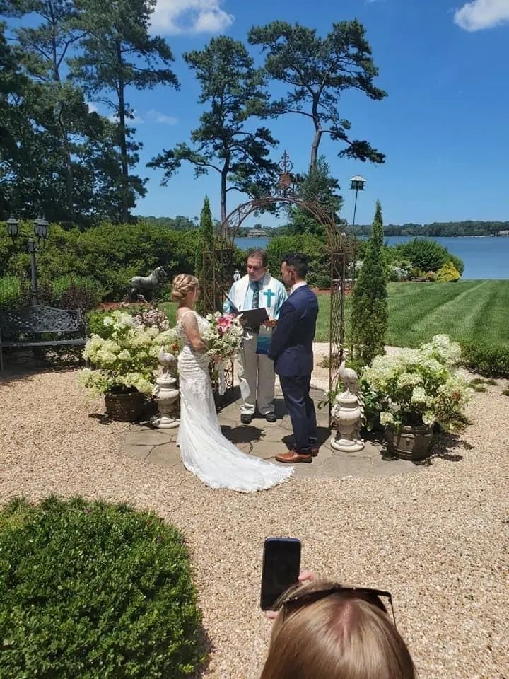 A bride and groom are getting married in front of a lake.