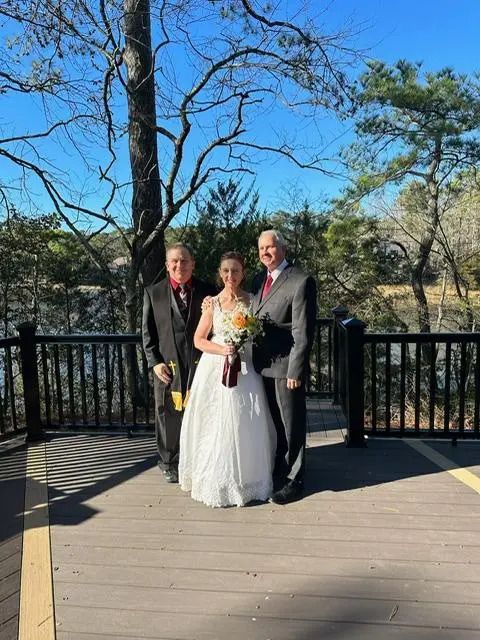 A bride and groom are posing for a picture on a deck.