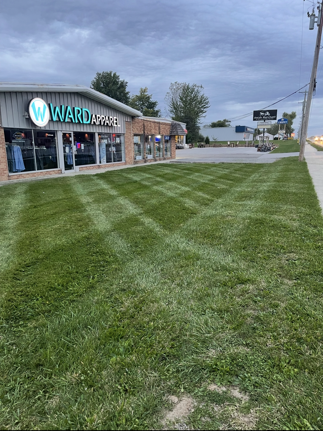 A storefront with a lawn in front on a cloudy day.