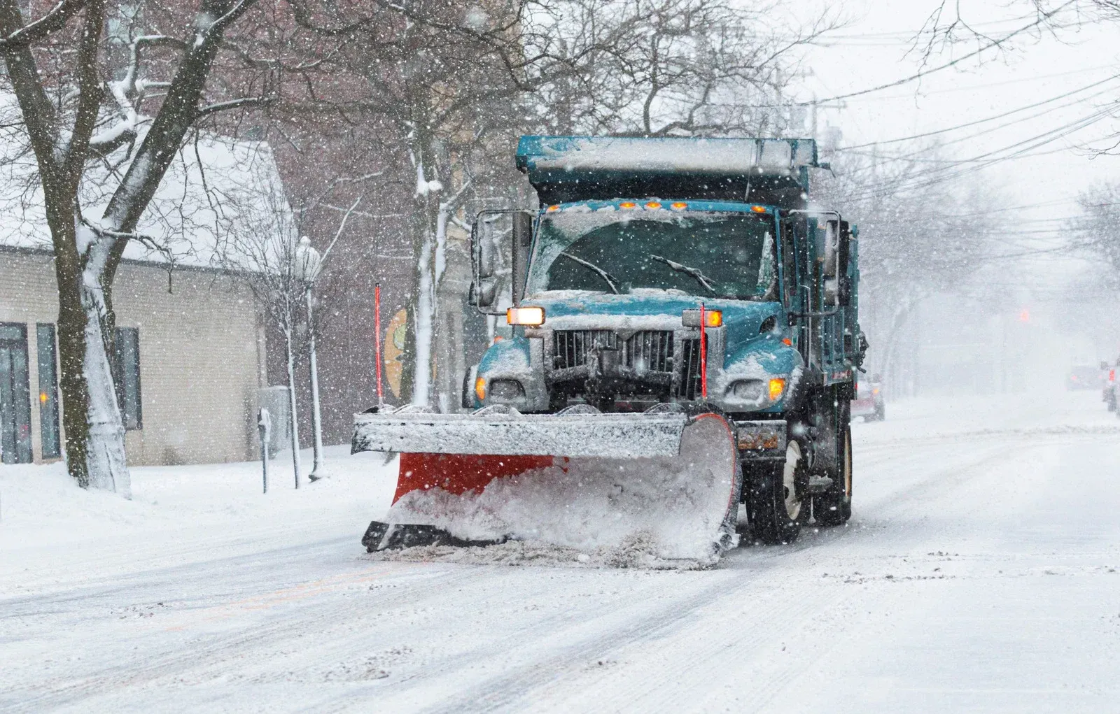 Snowplow clearing snow from a street during a winter storm.