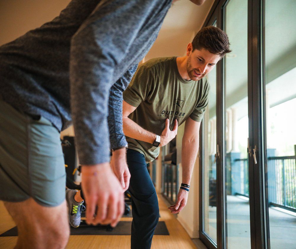 Two men are standing next to each other in a room looking out a window.