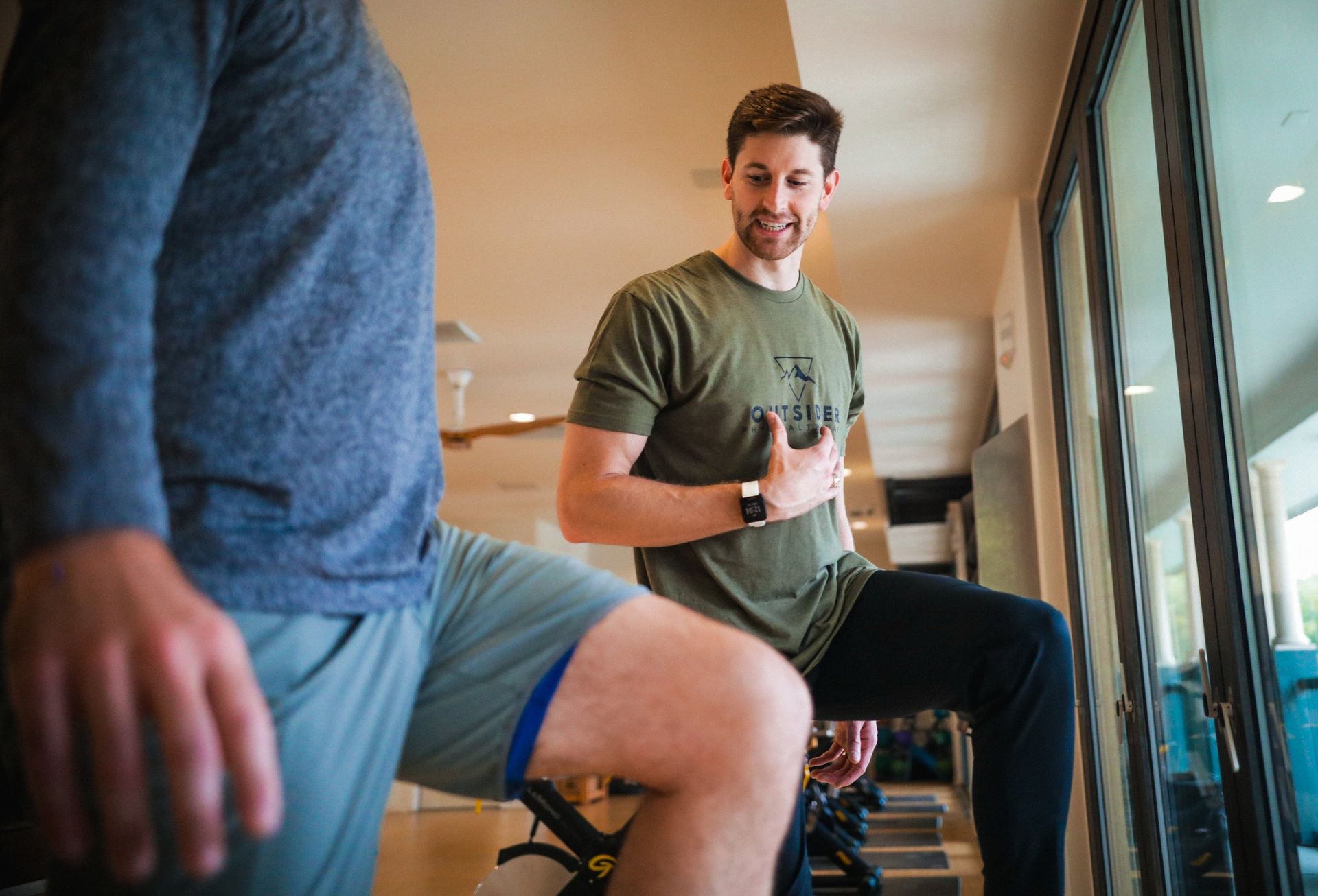 Two men are doing stretching exercises in a gym.