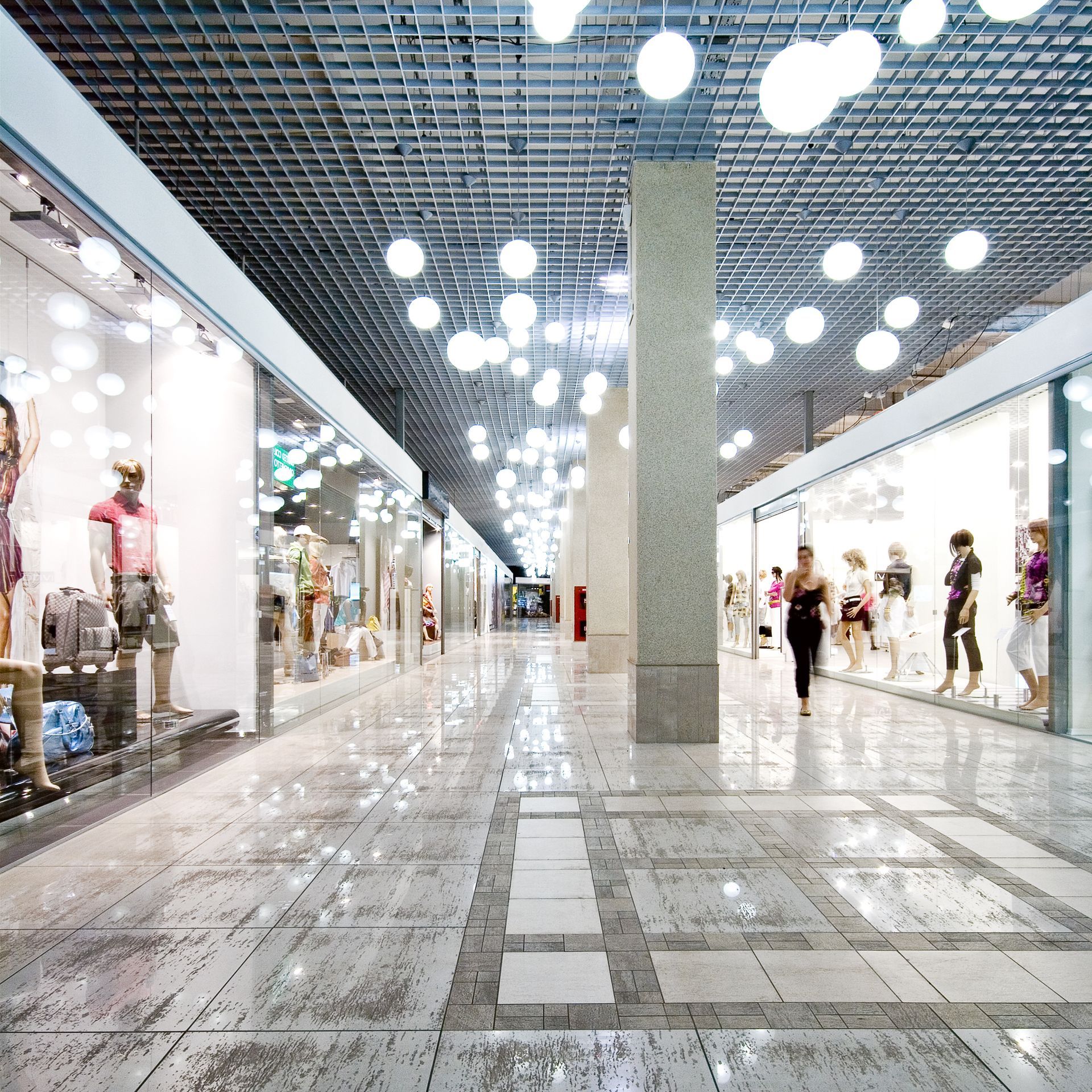 A woman is walking down a shopping mall aisle