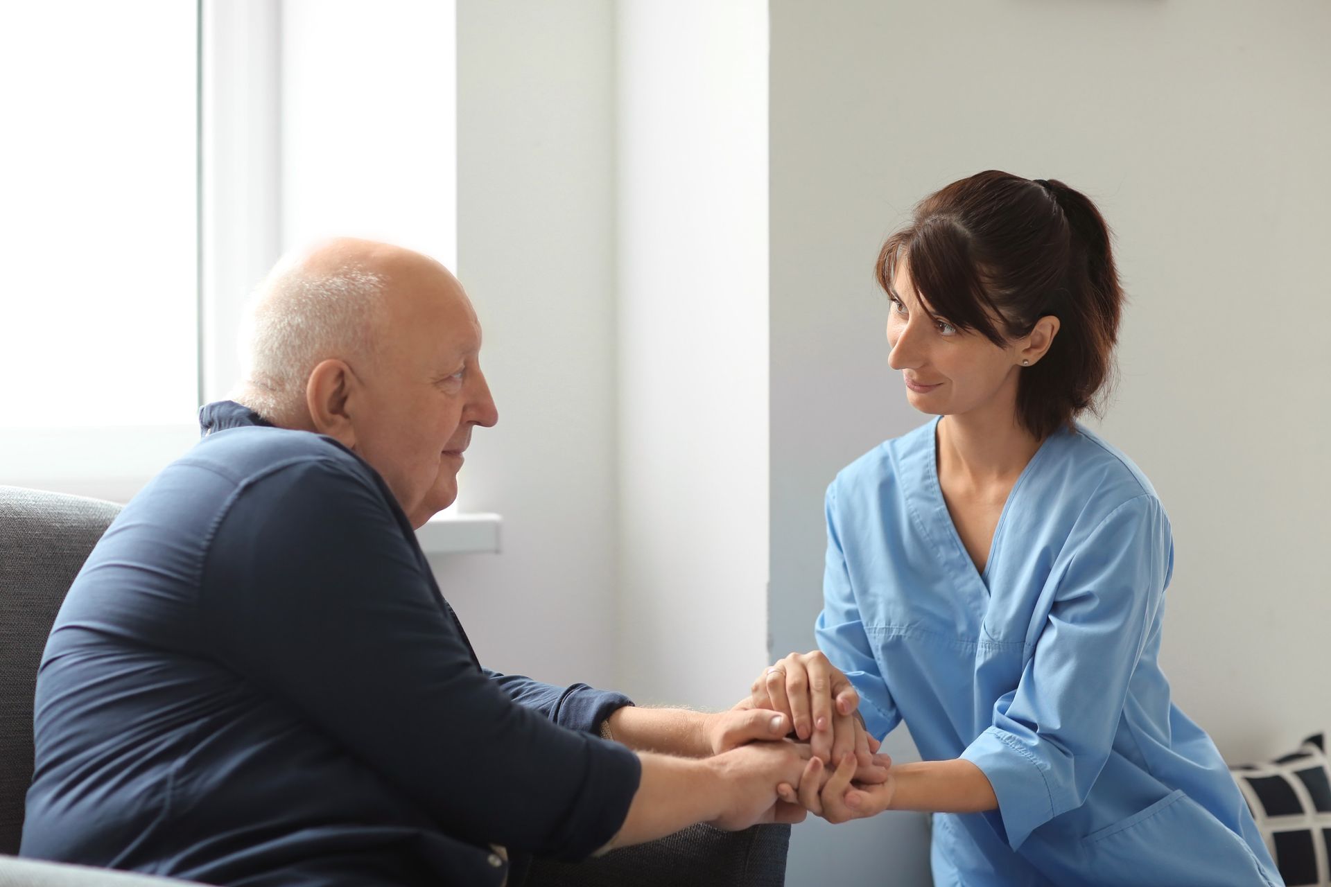 Elderly man with a cane is assisted by a nurse in a white coat, walking outside a building.